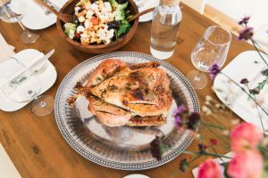 Turkey on a serving tray surrounded by thanksgiving foods and cutlery. 